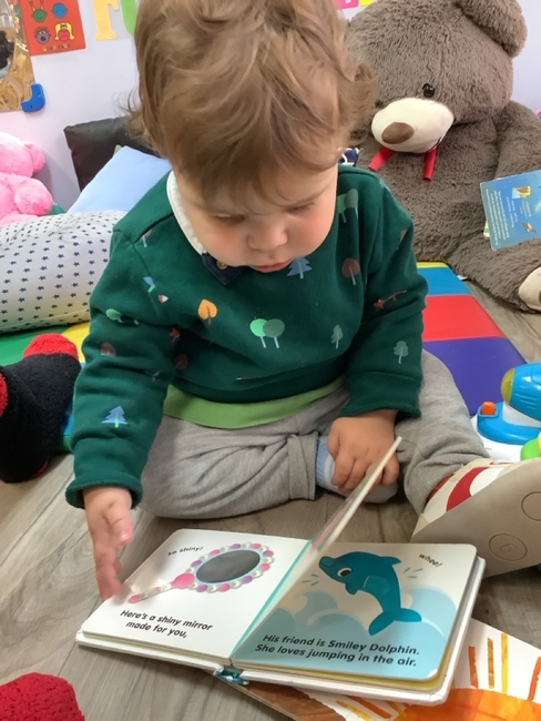Small kid sitting playing reading book in daycare